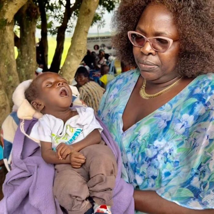 Woman holding a sleeping baby outdoors.